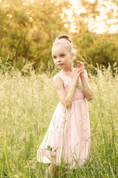 Linda menina em um vestido branco posando na grama — Fotografia de Stock