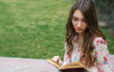 Young woman is reading a book in the city park.  Mindfulness, fa