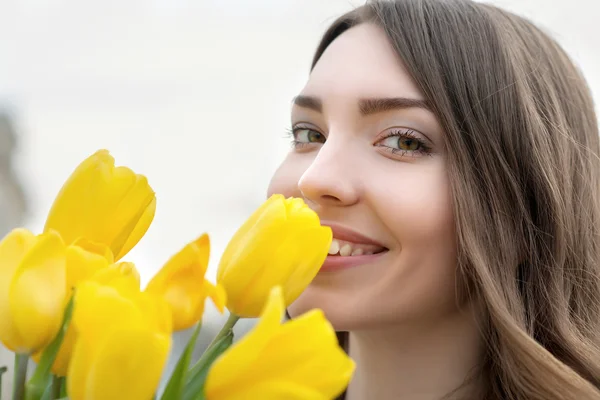 Young woman is yellow tulips flowers in the city. — Stok fotoğraf