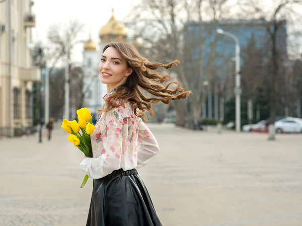 Mujer joven es tulipanes amarillos flores en la ciudad . — Foto de Stock