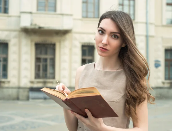 Girl with book and yellow tulips in city park reading — Stock Photo, Image