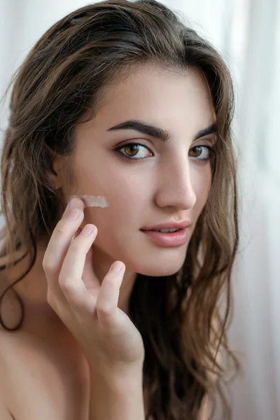 Beautiful model with wet hair in a towel after a shower applying — Stock Photo, Image