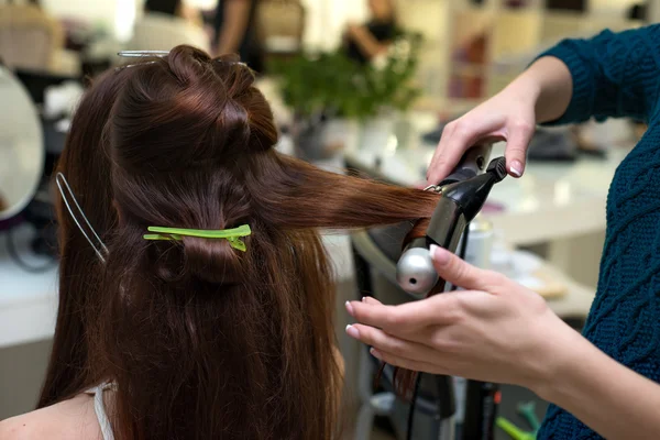 Hårstylist gør ringlets til brunette kvinde. Frisørarbejde - Stock-foto