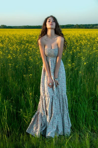 Schöne junge Frau mit Sonnenblume posiert in den Sonnenblumen — Stockfoto