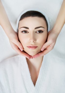 young relaxing beautiful woman having facial massage 