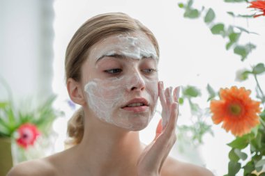 Yüzü kozmetik cilt köpüğü, jöle ya da sabunla temizleyen güzel bir genç kız. Kadın hame SPA prosedürleri.