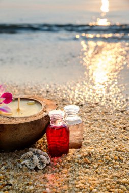 Petrol esanslı şişeler, deniz dalgalarında tropikal mum ve kabuk. Kaplıca ve sağlık seti kum ve dalga arkaplanı üzerine kurulur. Seçici odaklanma. Kapat..