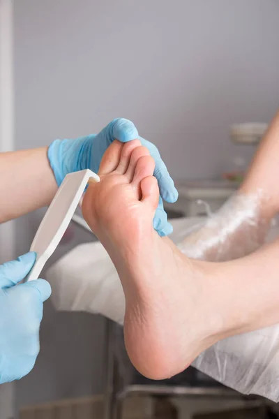 Peeling feet pedicure procedure. Pedicure SPA and foot care treatment and nail in the beauty salon. Scrub with pumice dead epidermis. Close up, selective focus.