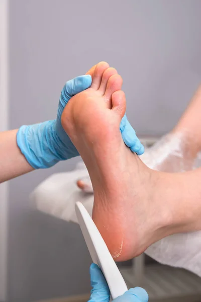 Peeling feet pedicure procedure. Pedicure SPA and foot care treatment and nail in the beauty salon. Scrub with pumice dead epidermis. Close up, selective focus.