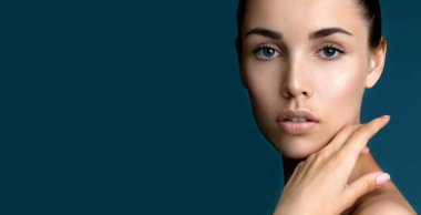 Temiz, taze tenli güzel bir kadın yüzüne dokunuyor. Doğal makyajlı, şekilli kaşları ve uzun kirpikleri olan güzellik modeli portresi. Spa, cilt bakımı ve sağlık.