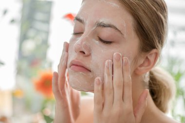 Yüzü kozmetik cilt köpüğü, jöle ya da sabunla temizleyen güzel bir genç kız. Kadın hame SPA prosedürleri.