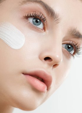 Yüzüne yüz kremi ya da maske süren genç bir kadın. Mükemmel taze cilde ve uzun kirpiklere sahip güzellik mankeni evde cildini önemser. Spa ve Sağlık, Cilt Bakımı Konsepti. Kapat, seçili odak.