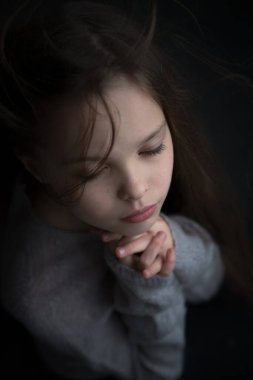 Dua eden küçük güzel bir kızın portresi. Yüz ifadesi. Çocuk ve duygular. İnanç ve İncil kavramı.