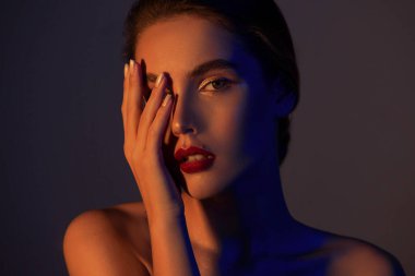 Neon altından stüdyo ışığı altında kusursuz cilde sahip güzel genç bir kadın. Doğal çıplak makyajlı ve uzun kirpikli güzellik modeli portresi..