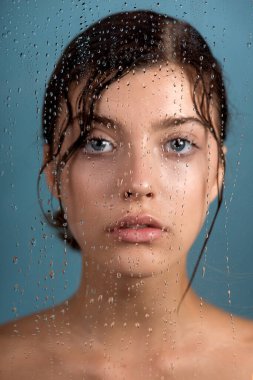 Temiz cildine ve su damlasına sahip genç ve güzel bir kadın yüzüne dokunuyor. Güzellik modelinin doğal çıplak makyajlı portresi cildini losyonla nemlendiriyor. Spa, cilt bakımı ve sağlık. Kapat, arkaplan, kopyala.
