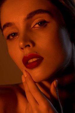 Neon altından stüdyo ışığı altında kusursuz cilde sahip güzel genç bir kadın. Doğal çıplak makyajlı ve uzun kirpikli güzellik modeli portresi..