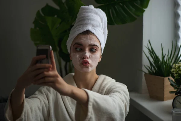 Young Woman Clay Facial Mask Makes Funny Face Her Phone — Stock Photo, Image