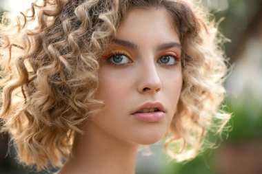 Dalgalı kıvırcık saçlı ve renkli makyajlı Güzel Moda Modeli 'nin Portresi. Makyaj ve saç. Saç bakım konsepti. Yakın çekim, Seçici odak.