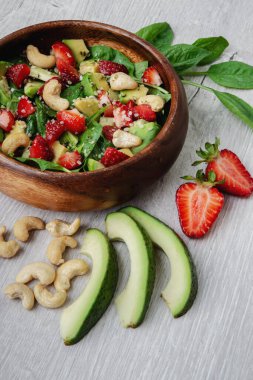 Avokado, roka, ıspanak, çilek, kaju ve tohumlu sağlıklı sebze salatası. Düşük karbonhidrat, düşük kalori diyeti. Sağlıklı beslenme, beslenme ve diyet konsepti. Yakın plan, seçici odaklanma. Üst manzara, düz uzanma.