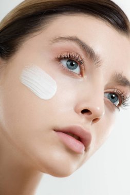 Yüzüne yüz kremi süren genç bir kadın. Mükemmel taze cilde ve uzun kirpiklere sahip güzellik mankeni evde cildini önemser. Spa ve Sağlık, Cilt Bakımı Konsepti.