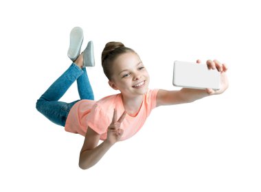 Akıllı telefon kullanıp uçan tatlı küçük kız. Çocuk modern teknoloji kullanıyor. Çocuk aletle selfie çekiyor, oyunlar oynuyor ve sohbet ediyor. Beyazda izole edilmiş.