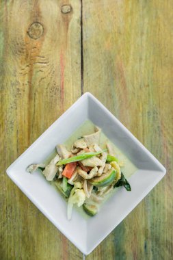 Ahşap arka planda tavuklu yeşil köri. Geleneksel Tayland yemekleri.