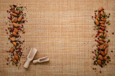 Hasır arka planda iki tahta kaşıkla hazırlanmış fındık ve tohumlar. Kopyalama alanı olan üst görünüm, düz yatay.