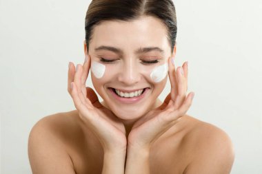 Yüzüne yüz kremi süren genç bir kadın. Mükemmel taze cilde ve uzun kirpiklere sahip güzellik mankeni evde cildini önemser. Spa ve Sağlık, Cilt Bakımı Konsepti. Kapat, seçili odak.