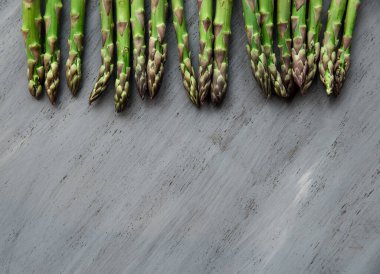 Gri bir arka planda kuşkonmaz. Sağlıklı beslenme ve vejetaryen yemekleri. Dikkat çekmeyen, seçici odaklanma. Üst görünüm, düz görünüm, kopyalama alanı.