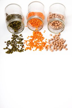 İçinde kuru bezelye, mercimek ve fasulye tohumları olan cam kavanozlar. Beyaz arkaplanda izole.