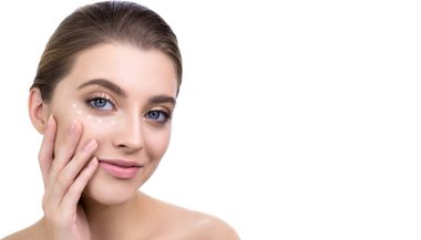 Genç bir kadın yüzüne göz kremi sürüyor. Taze ve uzun kirpikleri olan güzellik mankeni beyaz teniyle ilgilenir. Spa ve Sağlık, Cilt Bakımı Konsepti.