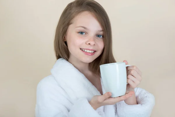 Beyaz Fincanlı Küçük Kız Bornozlu Çocuk Temiz Bir Kupayı Işaret — Stok fotoğraf
