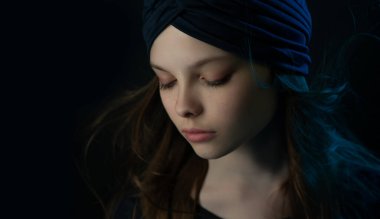 Çok renkli ışıklarla meditasyon yapan küçük güzel bir kız. Sarıklı ve dalgalı saçlı bir çocuğun koyu portresi duyguları gösteriyor. Seçici odaklanma, düşük tuş.