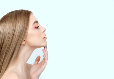 Mükemmel cilde ve doğal makyaja sahip, tropik yeşil yaprakların önünde poz veren güzel genç bir kadın. Yüzünün ve vücudunun gençlik modeli. SPA, sağlık, vücut bakımı ve cilt bakımı.