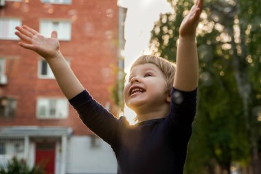 Mutlu gülümseyen küçük çocuk dışarıda oynuyor ve gülüyor. Yüz ifadesi, çocuk ve duygu..