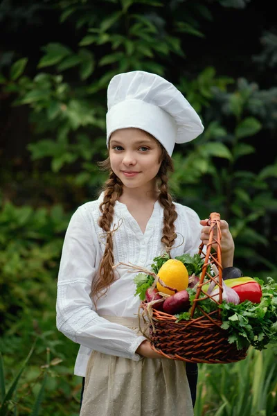 Schöne Kleine Mädchen Mit Kochmütze Und Einem Korb Mit Gemüse — Stockfoto