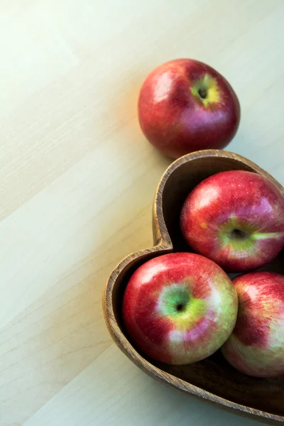 Äpfel im herzförmigen Holzteller auf dem Tisch, Nahaufnahme — Stockfoto