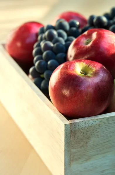 Äpfel und Trauben in einer Holzkiste, Nahaufnahme, selektiver Fokus — Stockfoto