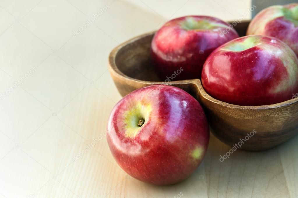 Apples in the wooden heart shape plate on the table, close up