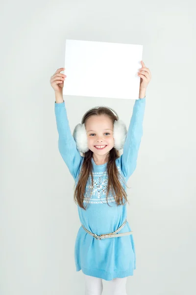 Cute girl in winter clothes with a white blank paper sheet. — Stock Photo, Image
