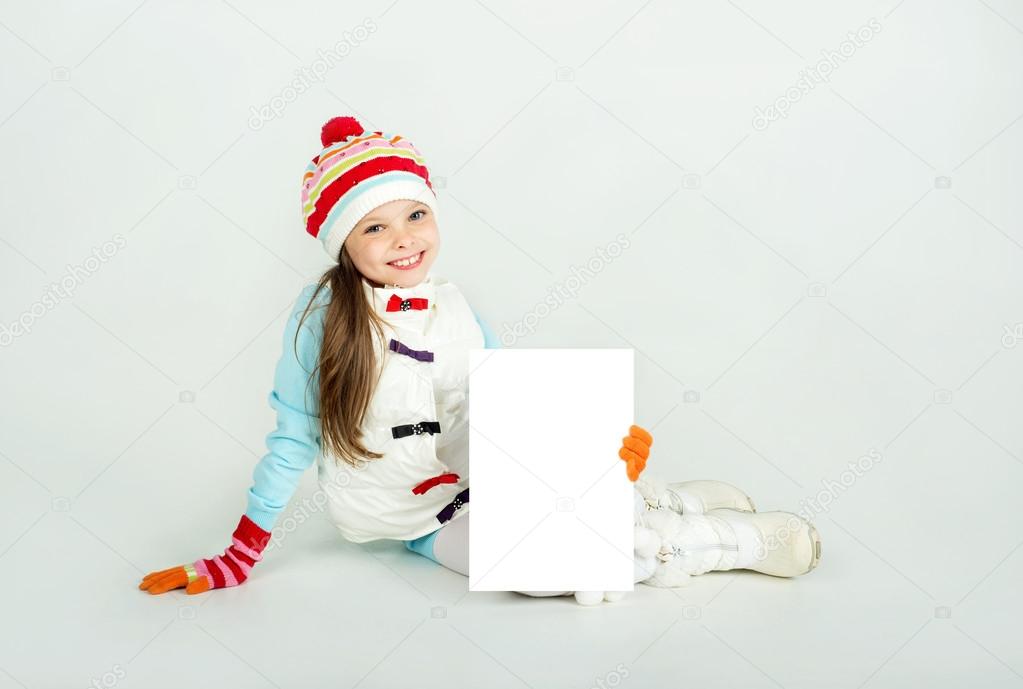 Cute girl in winter clothes with a white blank paper sheet.
