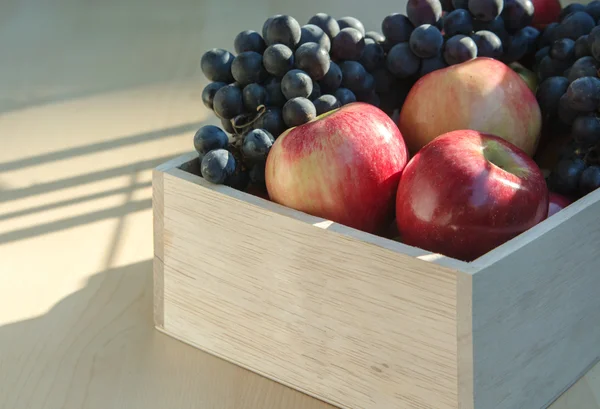 Jabłka i winogrona w drewniane pudełko — Zdjęcie stockowe