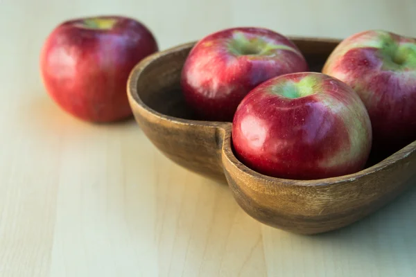 Äpfel im hölzernen herzförmigen Teller — Stockfoto