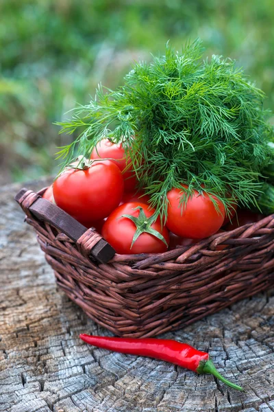 Basket and wooden plate with fresh vegetables — Stock Photo, Image
