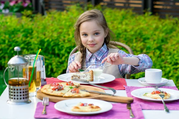 かわいい女の子の食卓に座って、食べる — ストック写真