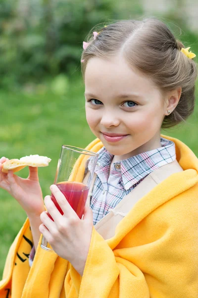 Süßes kleines Mädchen isst Snack und trinkt Saft — Stockfoto