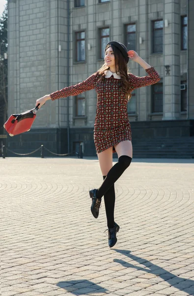 Beautiful brunette girl in stylish dress jumps — Stock Photo, Image