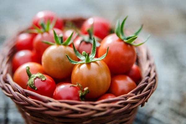 Tomates cerises dans un petit panier sur une vieille surface en bois — Photo