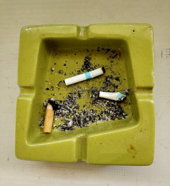 Ahşap arka planda izole edilmiş kül tablasında sigara kullanılmış..