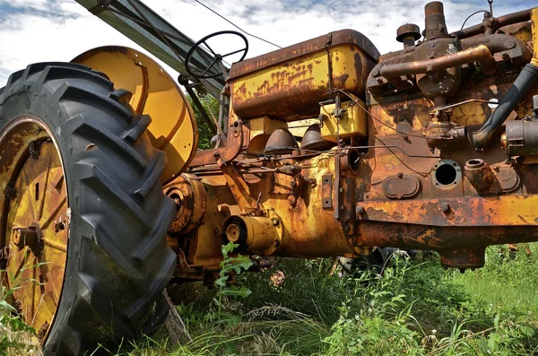 Oude roestige gele trekker — Stockfoto